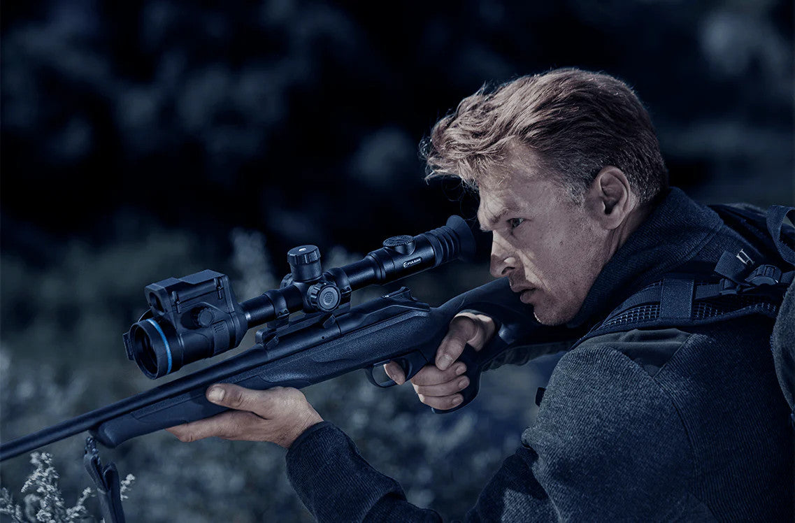 Man holding a rifle with a scope in a forest setting