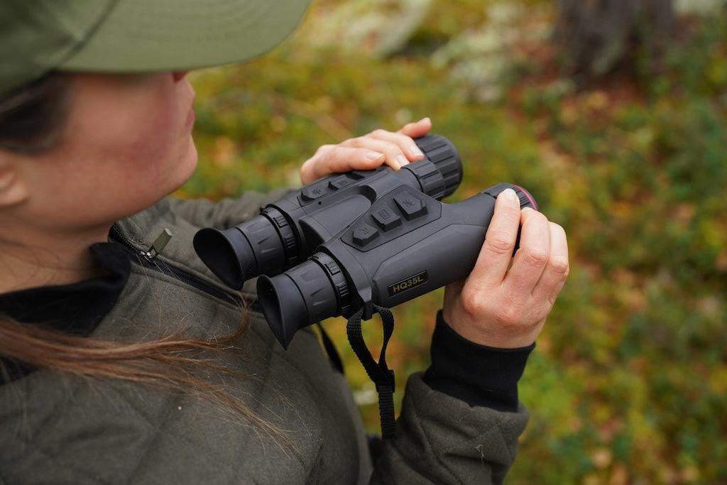 Woman holding a pair of binoculars in a natural setting